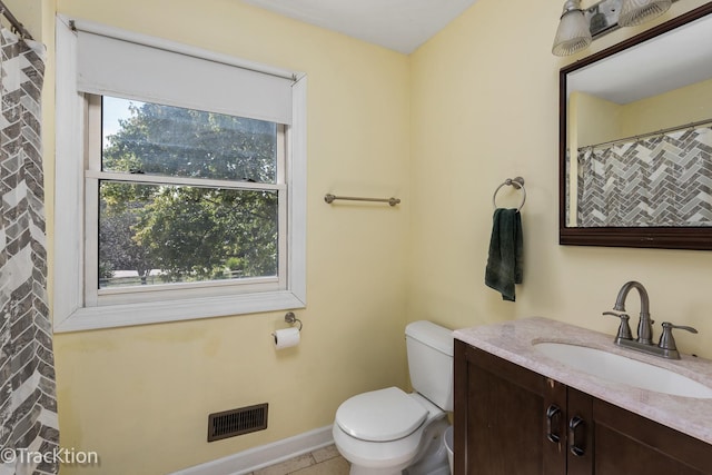 bathroom featuring tile patterned floors, a wealth of natural light, vanity, and toilet