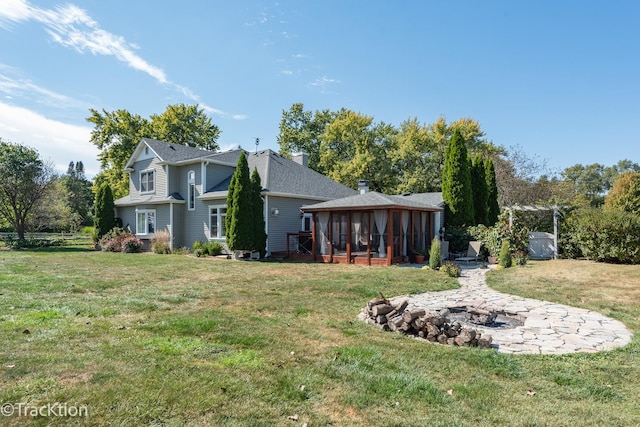 rear view of house featuring a sunroom and a yard