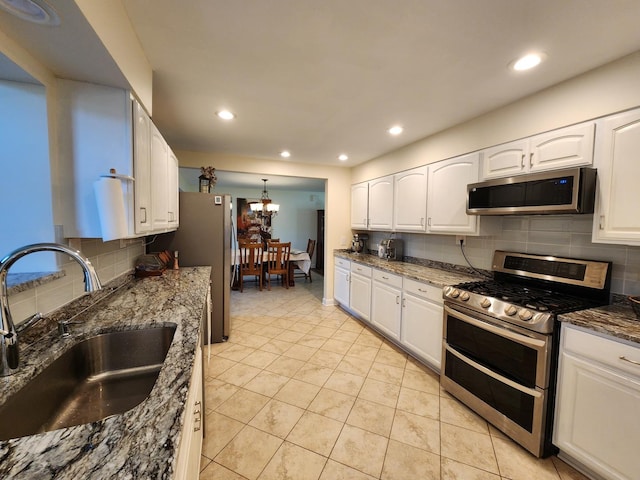 kitchen with dark stone countertops, white cabinetry, sink, and stainless steel appliances