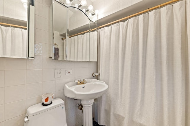 bathroom with a shower with shower curtain, decorative backsplash, toilet, and tile walls