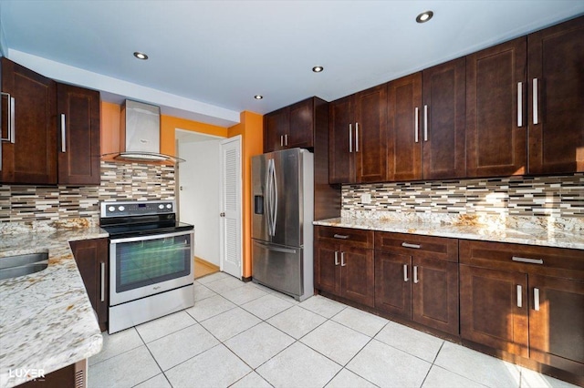 kitchen featuring decorative backsplash, appliances with stainless steel finishes, light stone counters, wall chimney exhaust hood, and light tile patterned floors