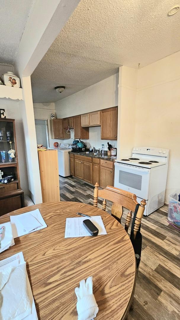 dining area with a textured ceiling, separate washer and dryer, dark wood-type flooring, and sink