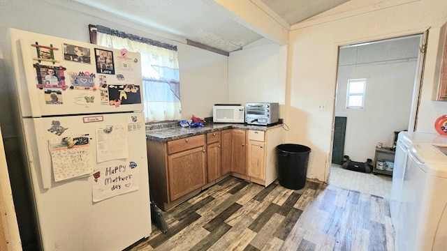 kitchen featuring vaulted ceiling, washer and dryer, dark hardwood / wood-style floors, and white appliances