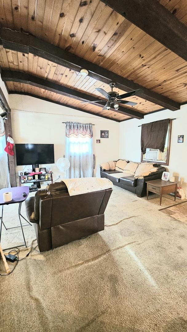 carpeted living room with beamed ceiling, ceiling fan, and wood ceiling