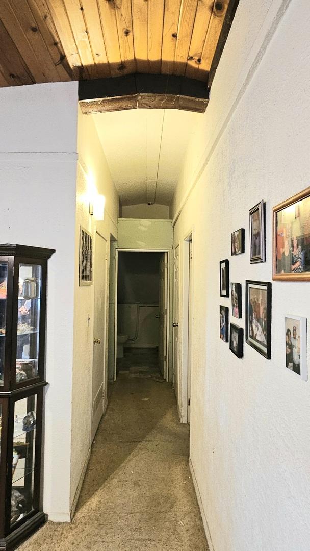 corridor with lofted ceiling with beams, carpet floors, and wood ceiling