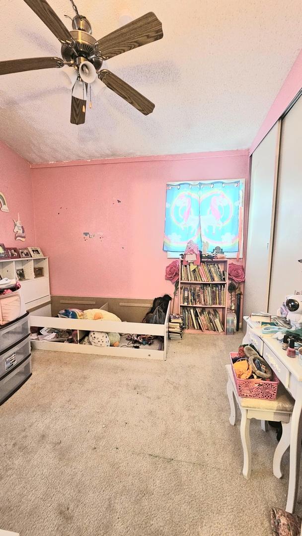 recreation room with ceiling fan, carpet, and a textured ceiling