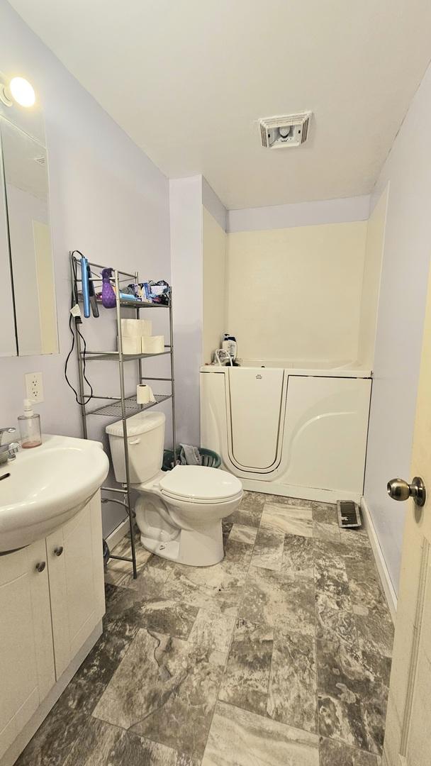 bathroom with vanity, a bath, and toilet