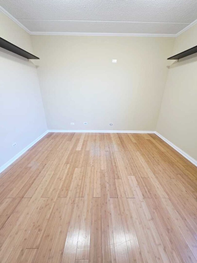 unfurnished room featuring light wood-type flooring, a textured ceiling, and crown molding