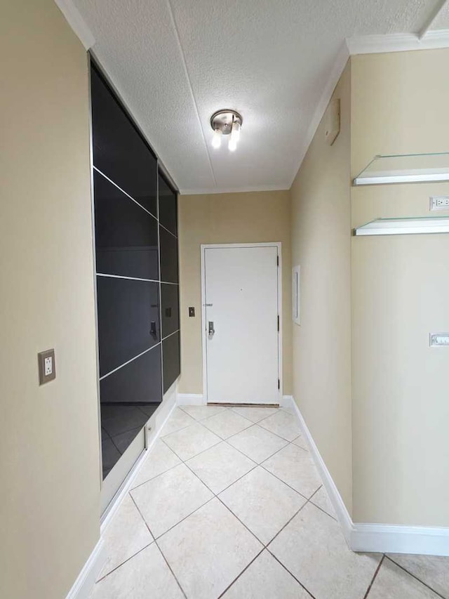 doorway to outside featuring ornamental molding, light tile patterned flooring, baseboards, and a textured ceiling