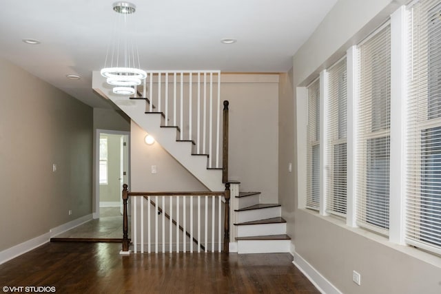 stairway with wood-type flooring and a notable chandelier