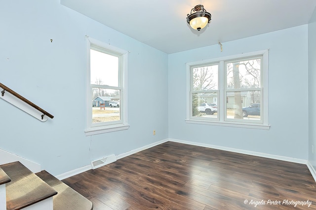 spare room with dark wood-type flooring and a wealth of natural light