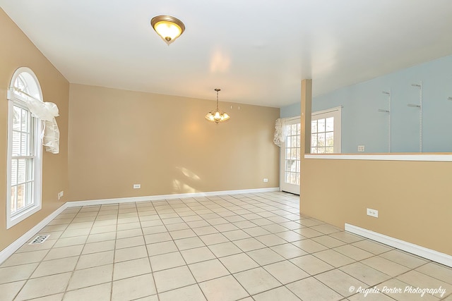 tiled empty room with a notable chandelier