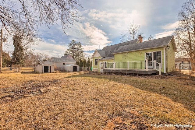 rear view of property with a wooden deck, a yard, and a storage unit