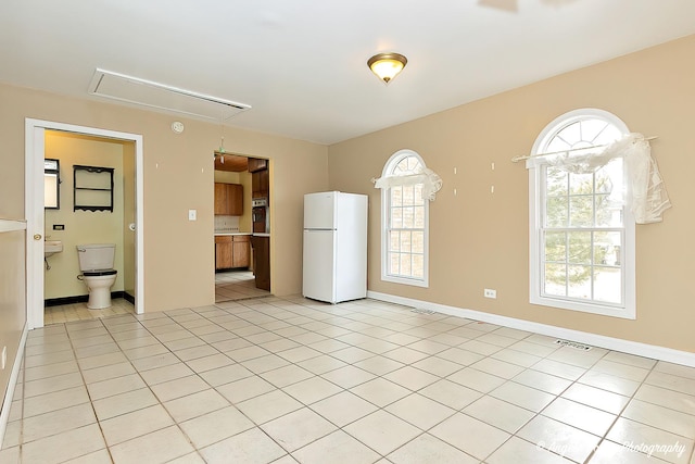 kitchen featuring light tile patterned flooring, oven, and white fridge