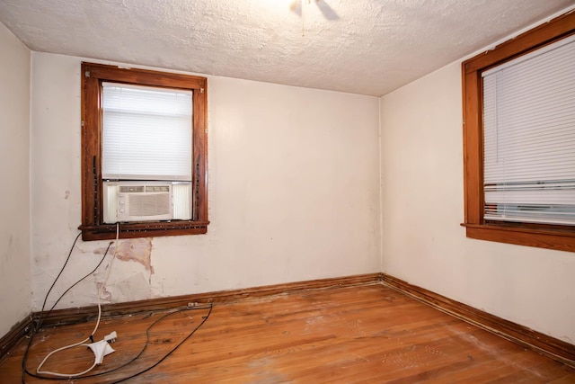 spare room featuring hardwood / wood-style floors, cooling unit, and a textured ceiling