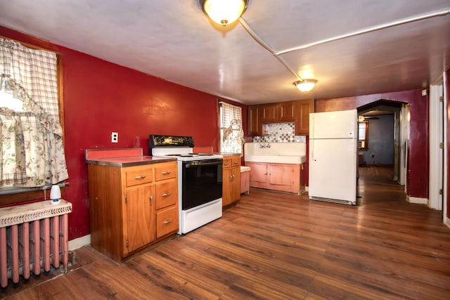 kitchen with white appliances, backsplash, sink, dark hardwood / wood-style floors, and radiator heating unit