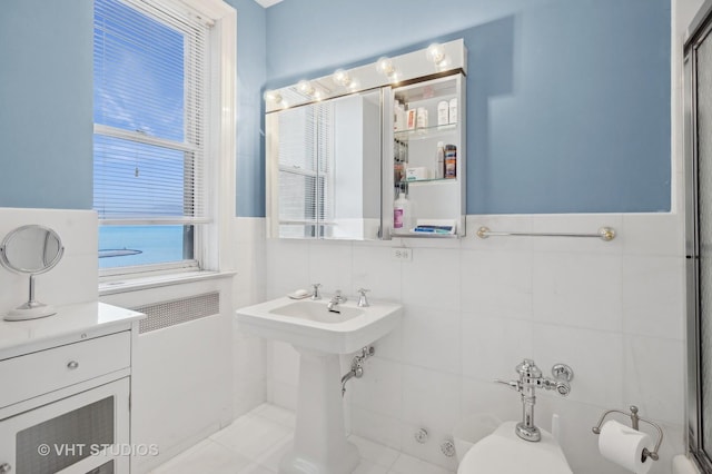 bathroom featuring tile patterned flooring, a water view, and tile walls