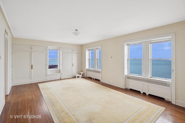 interior space featuring hardwood / wood-style flooring, a water view, and radiator heating unit