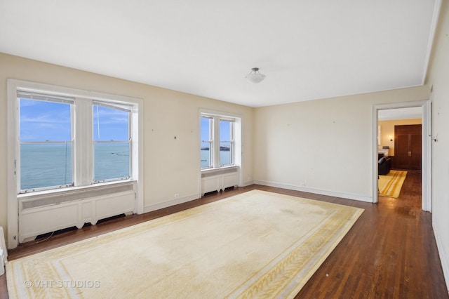 unfurnished room with radiator, hardwood / wood-style floors, and a water view