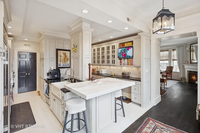 kitchen with a kitchen breakfast bar, a kitchen island with sink, sink, pendant lighting, and dark stone countertops