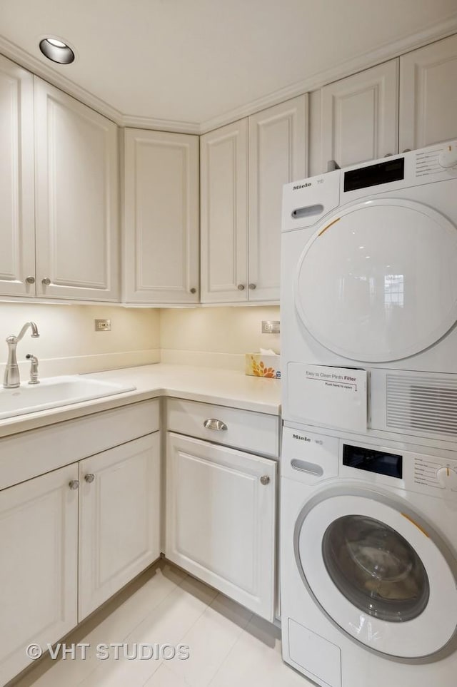 clothes washing area with cabinets, light tile patterned floors, stacked washer and clothes dryer, and sink