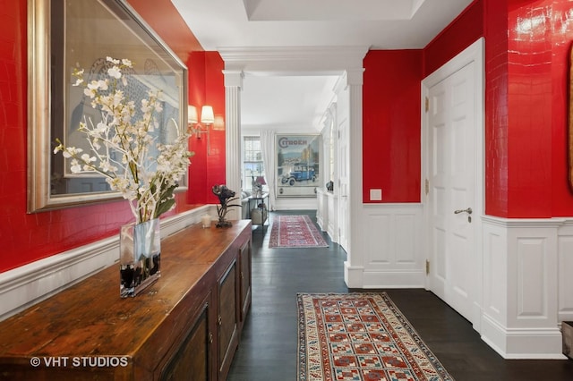 hallway featuring dark wood-type flooring and decorative columns