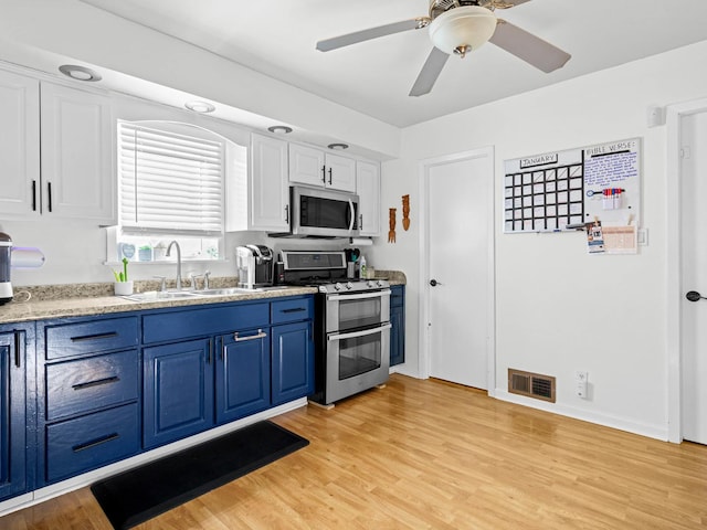 kitchen featuring blue cabinetry, white cabinetry, sink, stainless steel appliances, and light hardwood / wood-style floors