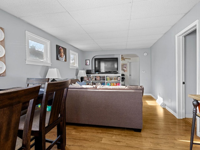 living room featuring hardwood / wood-style floors, a drop ceiling, and ceiling fan