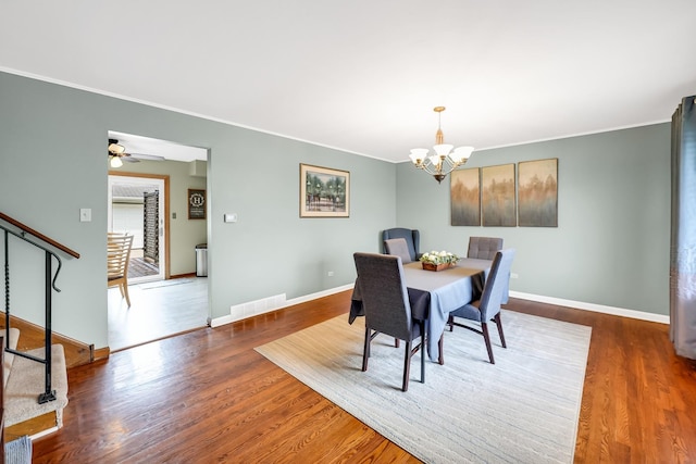 dining area featuring ceiling fan with notable chandelier, dark hardwood / wood-style flooring, and ornamental molding