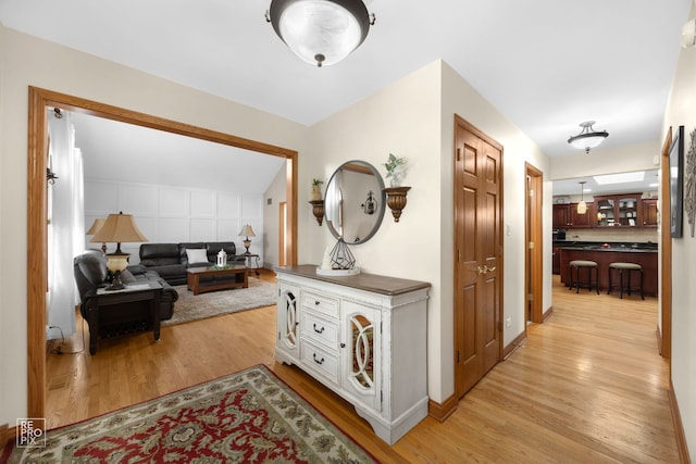 hallway with light hardwood / wood-style floors and vaulted ceiling