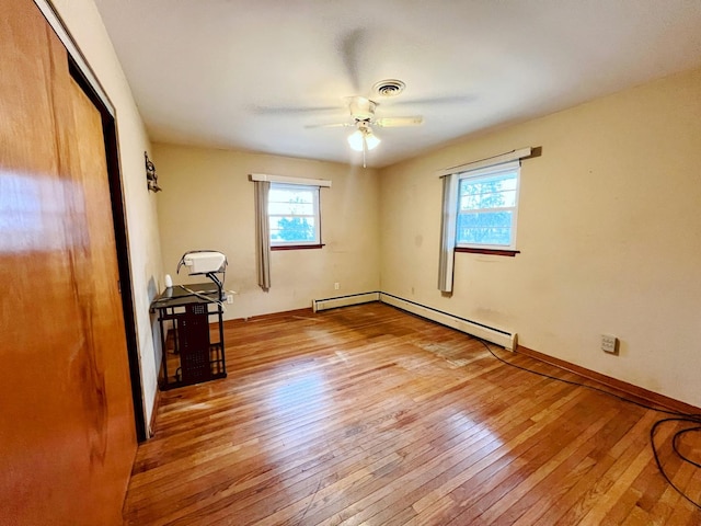 unfurnished bedroom featuring ceiling fan, a baseboard heating unit, and light hardwood / wood-style flooring