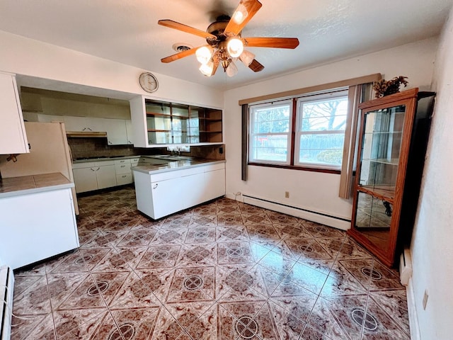 kitchen with ceiling fan, white cabinetry, sink, and a baseboard heating unit