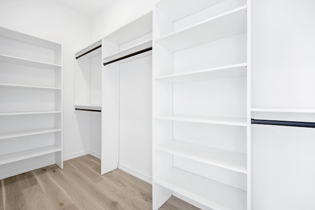 walk in closet with light hardwood / wood-style flooring