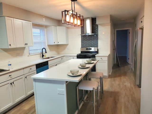 kitchen featuring appliances with stainless steel finishes, a kitchen breakfast bar, a kitchen island, wall chimney range hood, and white cabinetry