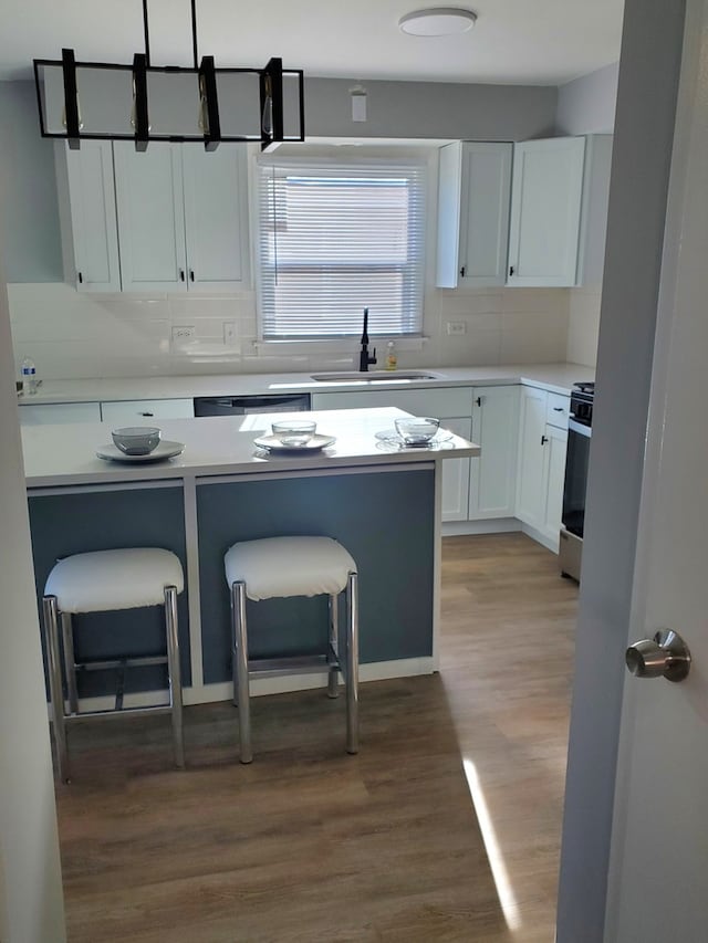 kitchen with white cabinets, a breakfast bar, and wood-type flooring