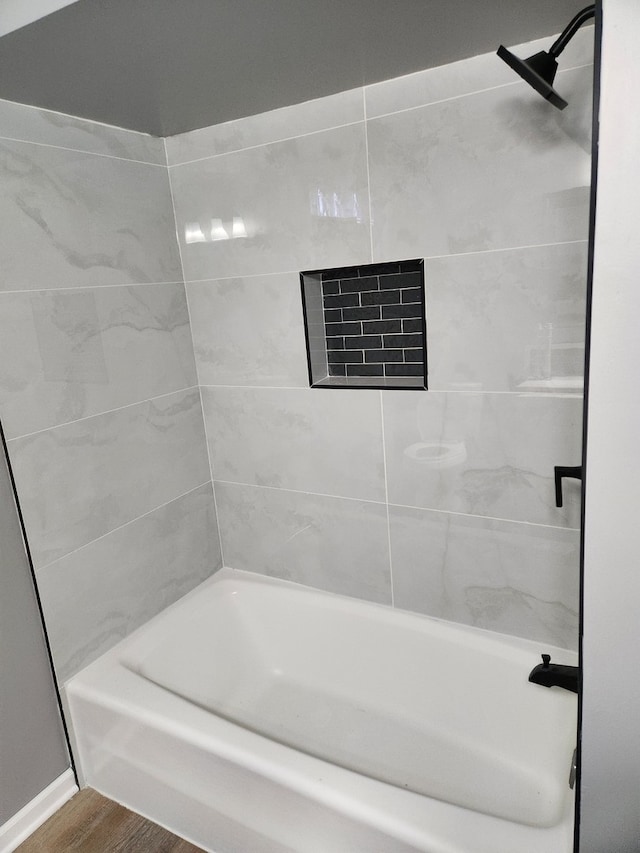 bathroom with hardwood / wood-style floors and tiled shower / bath