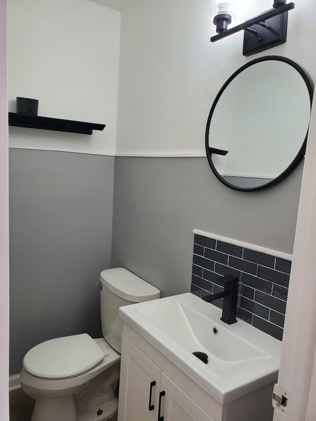 bathroom featuring vanity, toilet, and tasteful backsplash