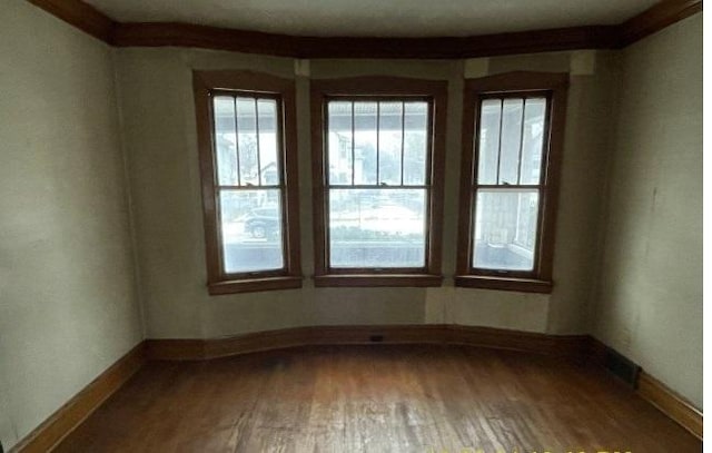 spare room with hardwood / wood-style flooring and ornamental molding