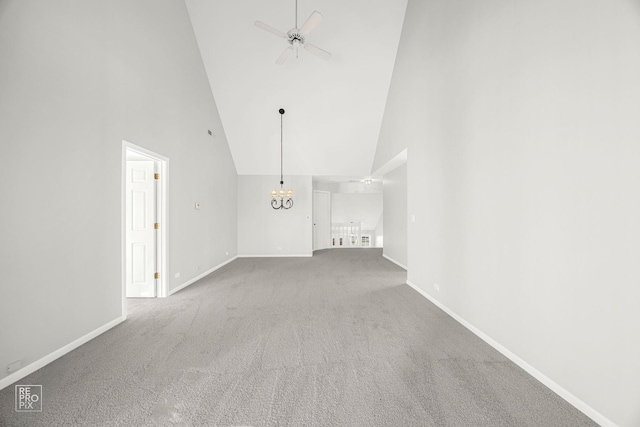 unfurnished living room with high vaulted ceiling, carpet floors, and ceiling fan with notable chandelier