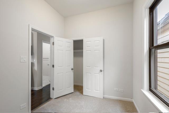 unfurnished bedroom with light carpet and a closet