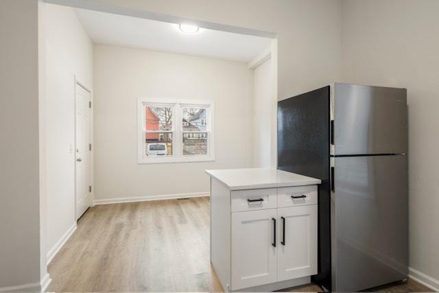 kitchen with white cabinets, stainless steel fridge, and light wood-type flooring