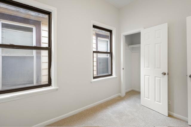 unfurnished bedroom featuring light colored carpet and a closet