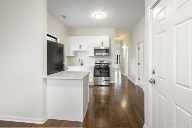 kitchen with white cabinets, sink, dark hardwood / wood-style flooring, kitchen peninsula, and stainless steel appliances