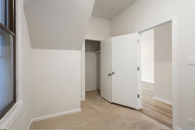 unfurnished bedroom featuring light colored carpet and lofted ceiling