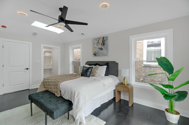 bedroom featuring a skylight, ceiling fan, a closet, and a spacious closet