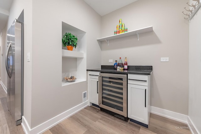 bar featuring white cabinetry, stainless steel fridge with ice dispenser, light hardwood / wood-style flooring, and beverage cooler