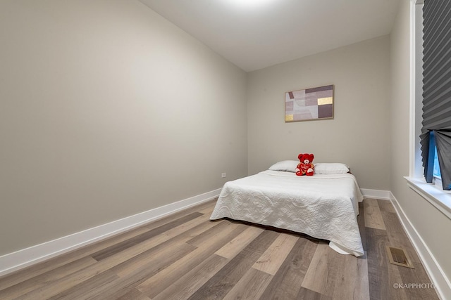 bedroom with hardwood / wood-style floors and lofted ceiling