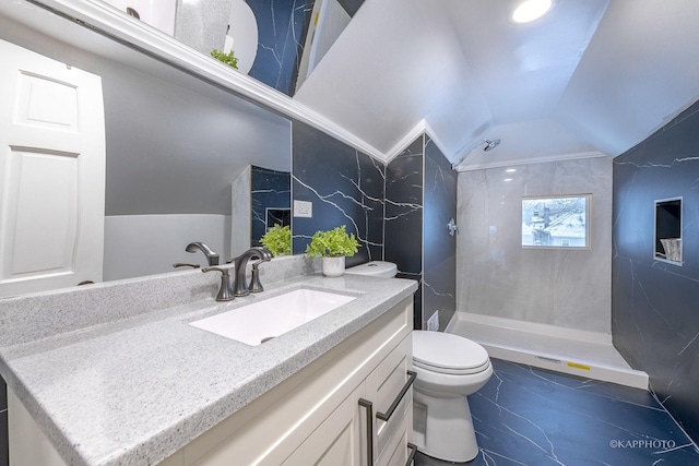 bathroom with vanity, toilet, a tile shower, and vaulted ceiling