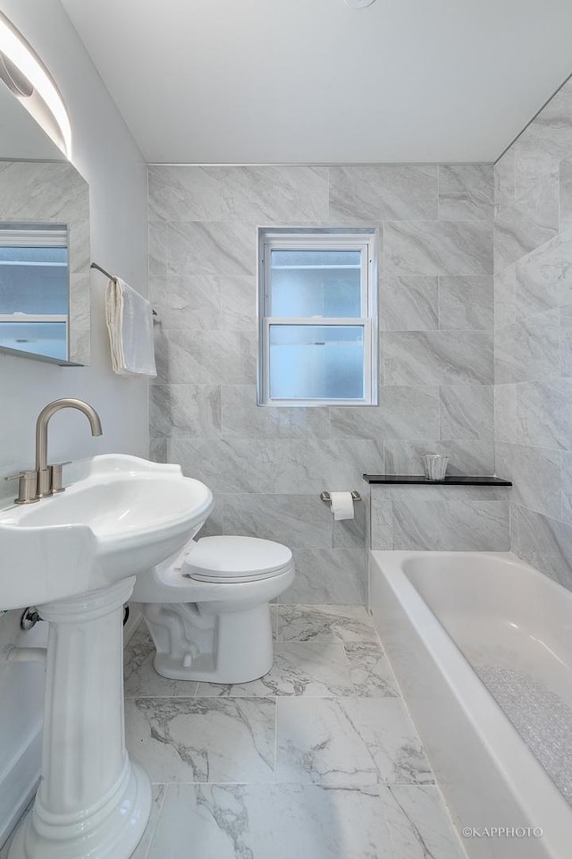 bathroom featuring a tub, tile walls, and toilet