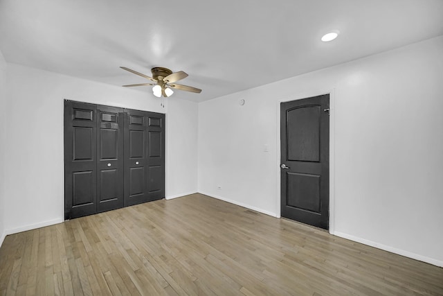 unfurnished bedroom featuring ceiling fan, light hardwood / wood-style floors, and a closet